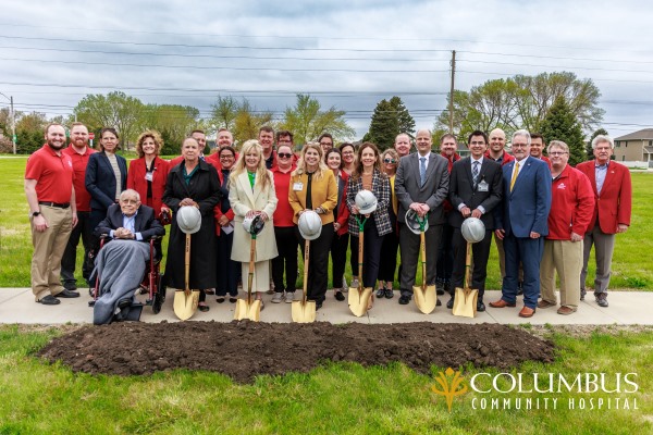 Bob Mead, sitting, with his daughters Anne (left, standing) and Kate (right, holding shovel) are joined with executives of the Columbus Community hospital as well as Columbus community ambassadors during the official groundbreaking ceremony.
