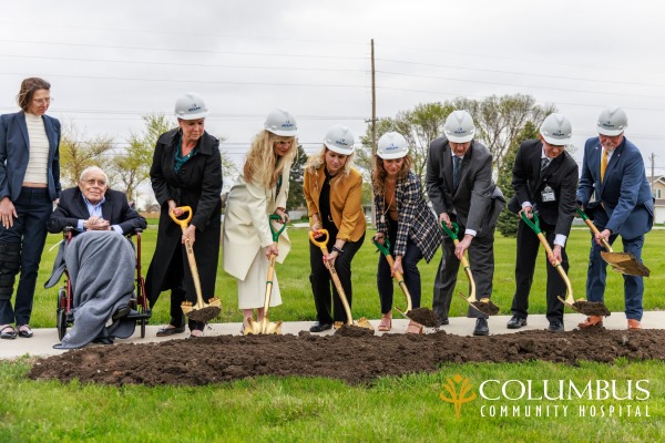 Bob Mead, sitting, with his daughters Anne (left, standing) and Kate (right, holding shovel) are joined with executives of the Columbus Community hospital during the official groundbreaking ceremony.